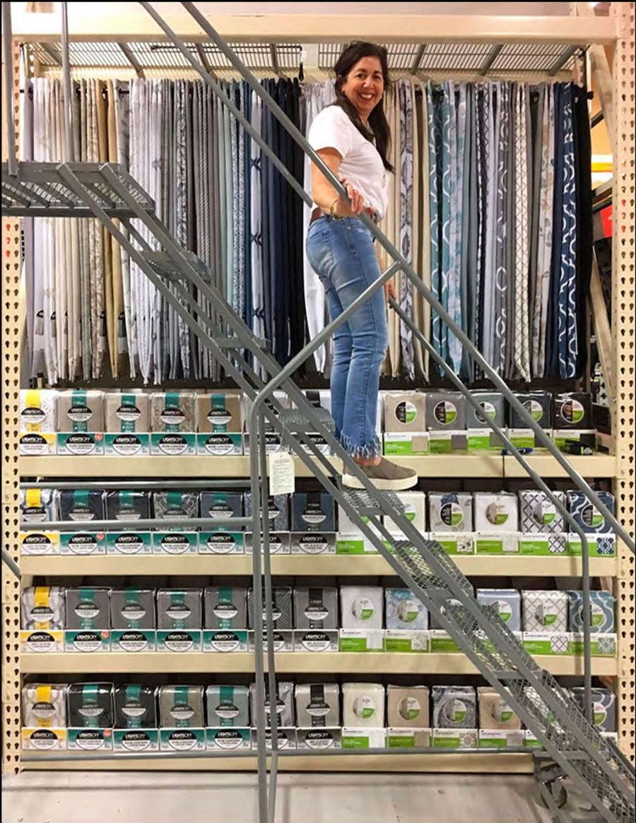 Our design lead on a ladder in a store aisle stocked with our window curtains