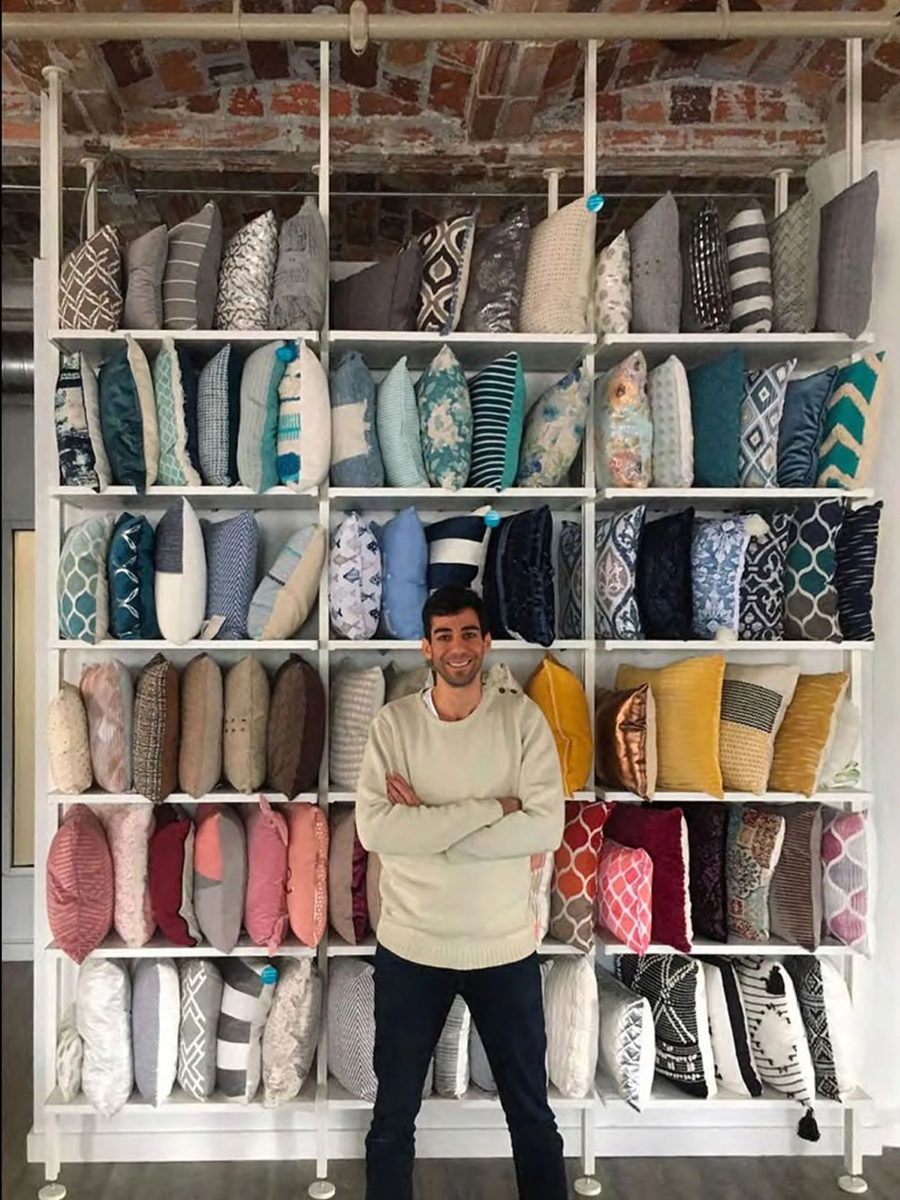 One of our sales team in front of a wall of our decorative pillows